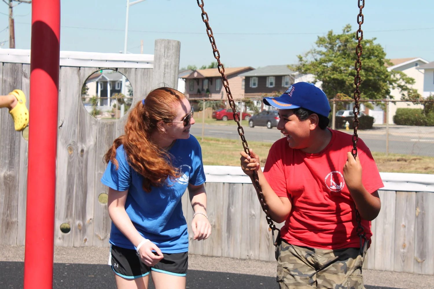 Two Camp ANCHOR campers laughing together on the swings